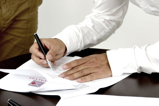 zdjęcie przedstawia mężczyznę ubranego w stylu biznesowym, który podpisuje pismo 