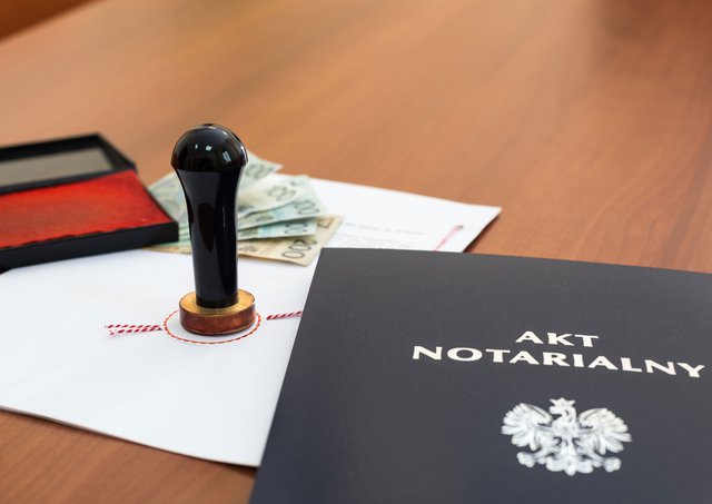 na zdjęciu leży na biurku akt notarialny, a obok niego pieczęć notariusza