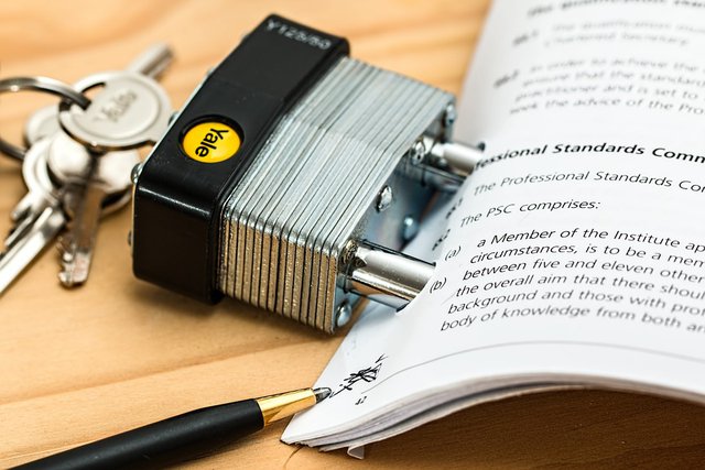 na zdjęciu widoczna jest zamknięta kłódka, której zamknięcie jest niewidoczne ponieważ znajduje się pod plikiem papieru