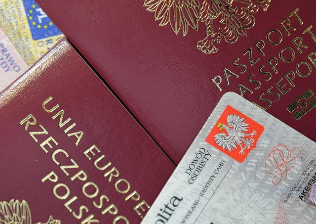 obraz przedstawia dokumenty polski paszport oraz dowód osobisty, które leżą jeden na drugim